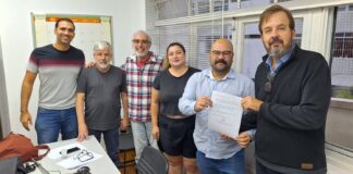 Chapa 1 — Resistir, Lutar e Avançar Comissão Eleitoral do Sindicato (Paulo Zocchi, Caroline Beraldo, João Marques, Décio Trujilo e Thiago Barolli) recebe do presidente do Sindicato, Thiago Tanji, a inscrição da Chapa 1, encabeçada por ele: compromisso de avançar na luta pelos direitos da categoria